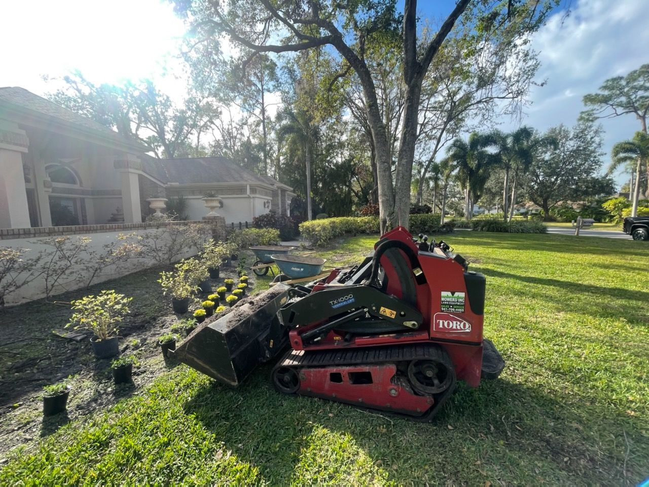 A small red tractor is parked in the grass in front of a house.