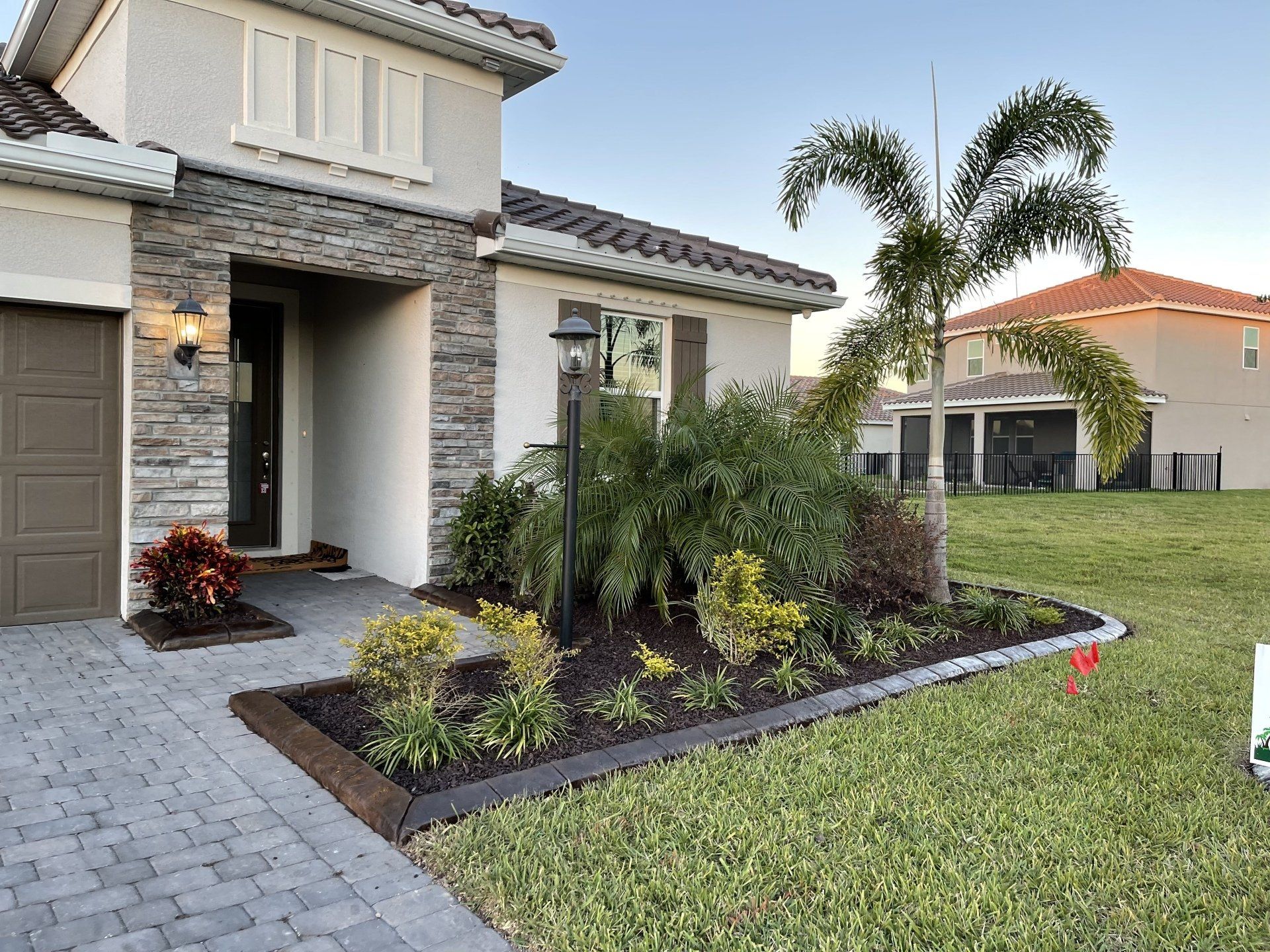 A house with a brick driveway and a palm tree in front of it.