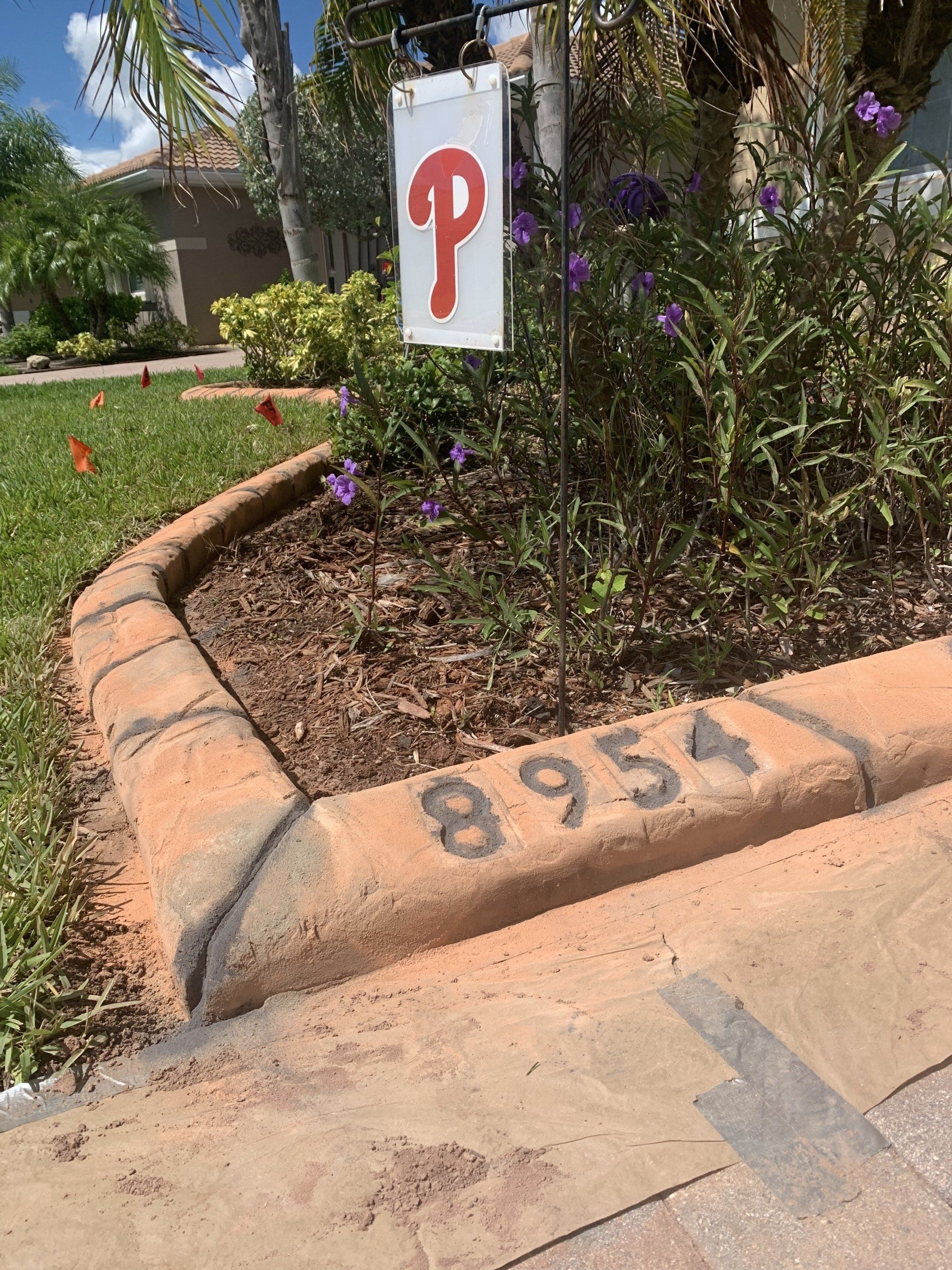 A sign with the letter p on it is in a garden.