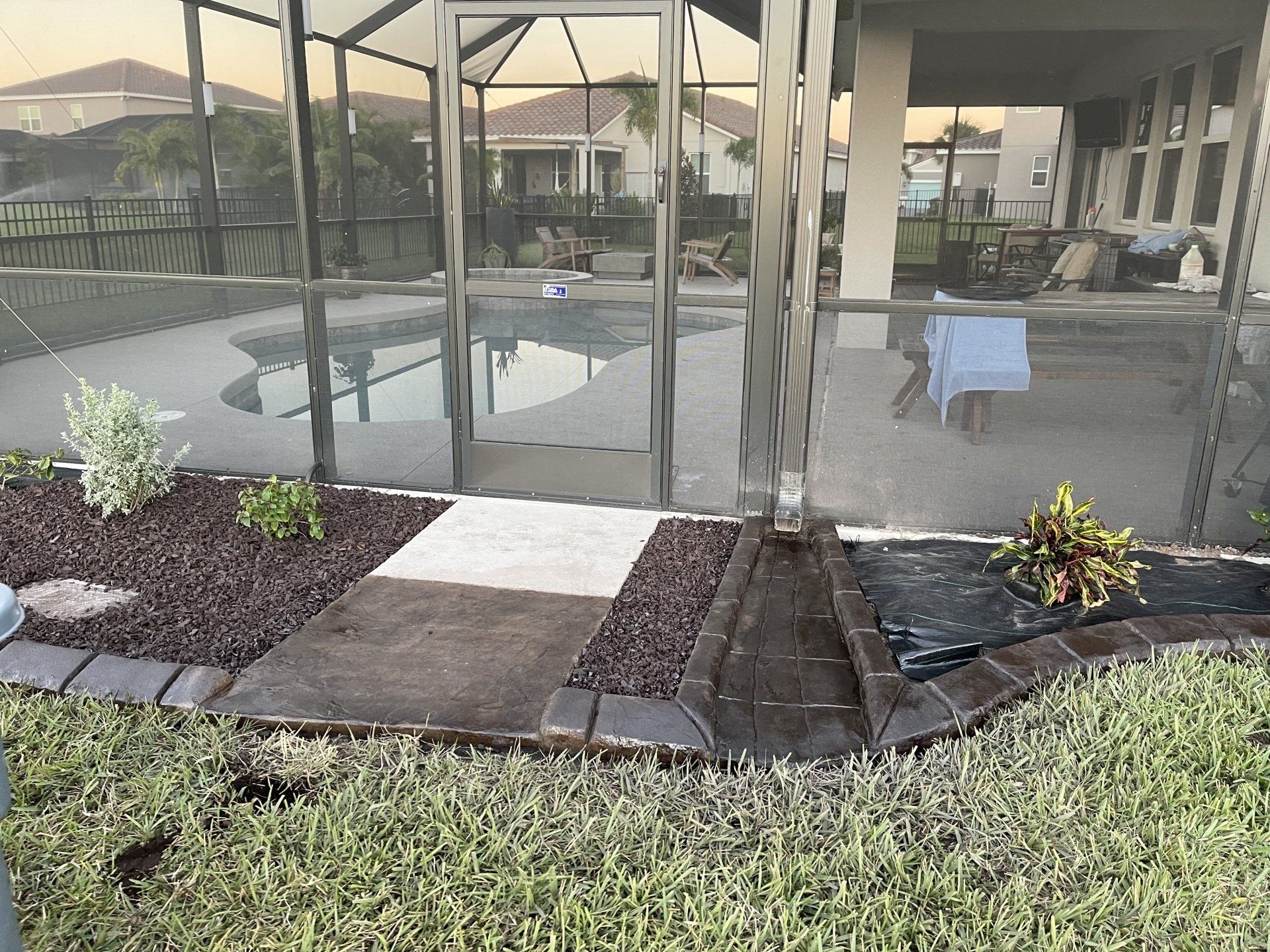 A screened in porch with a swimming pool in the background