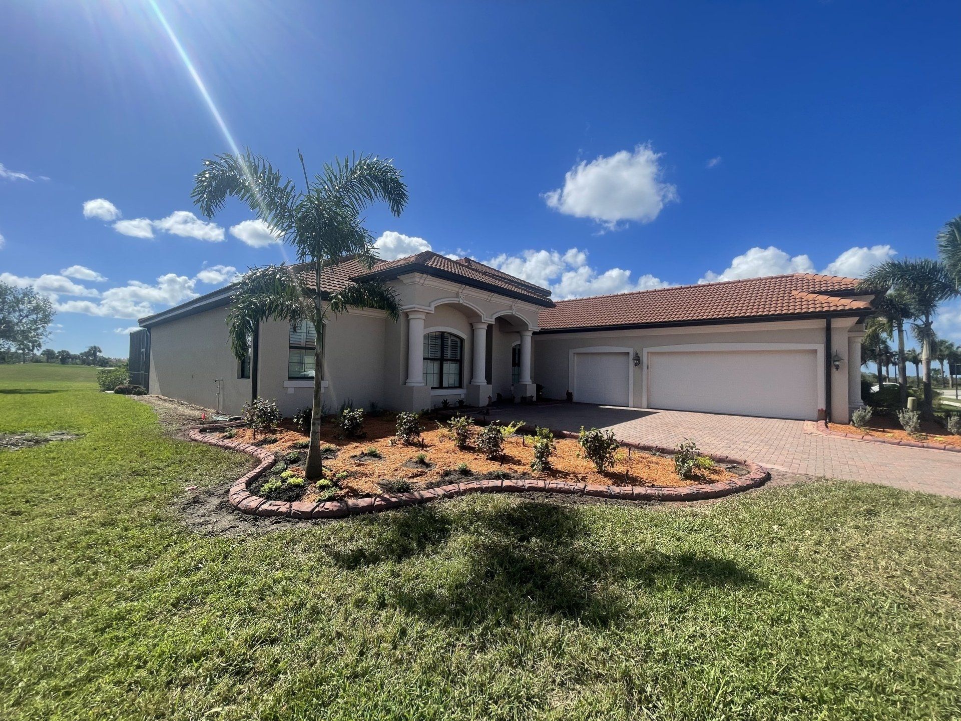 A large white house with a tile roof is sitting on top of a lush green field.