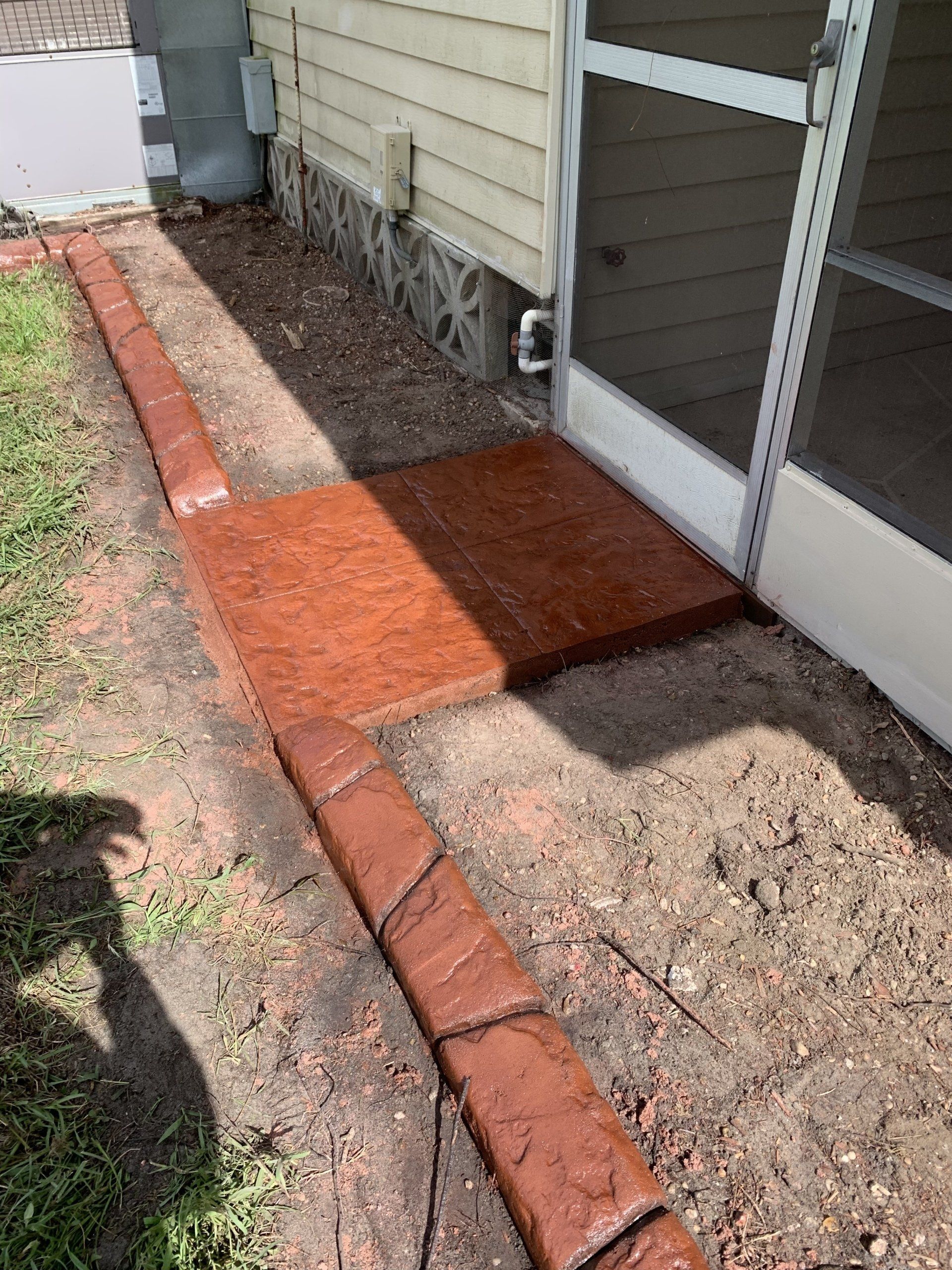 A brick walkway is being built in front of a screened in porch.