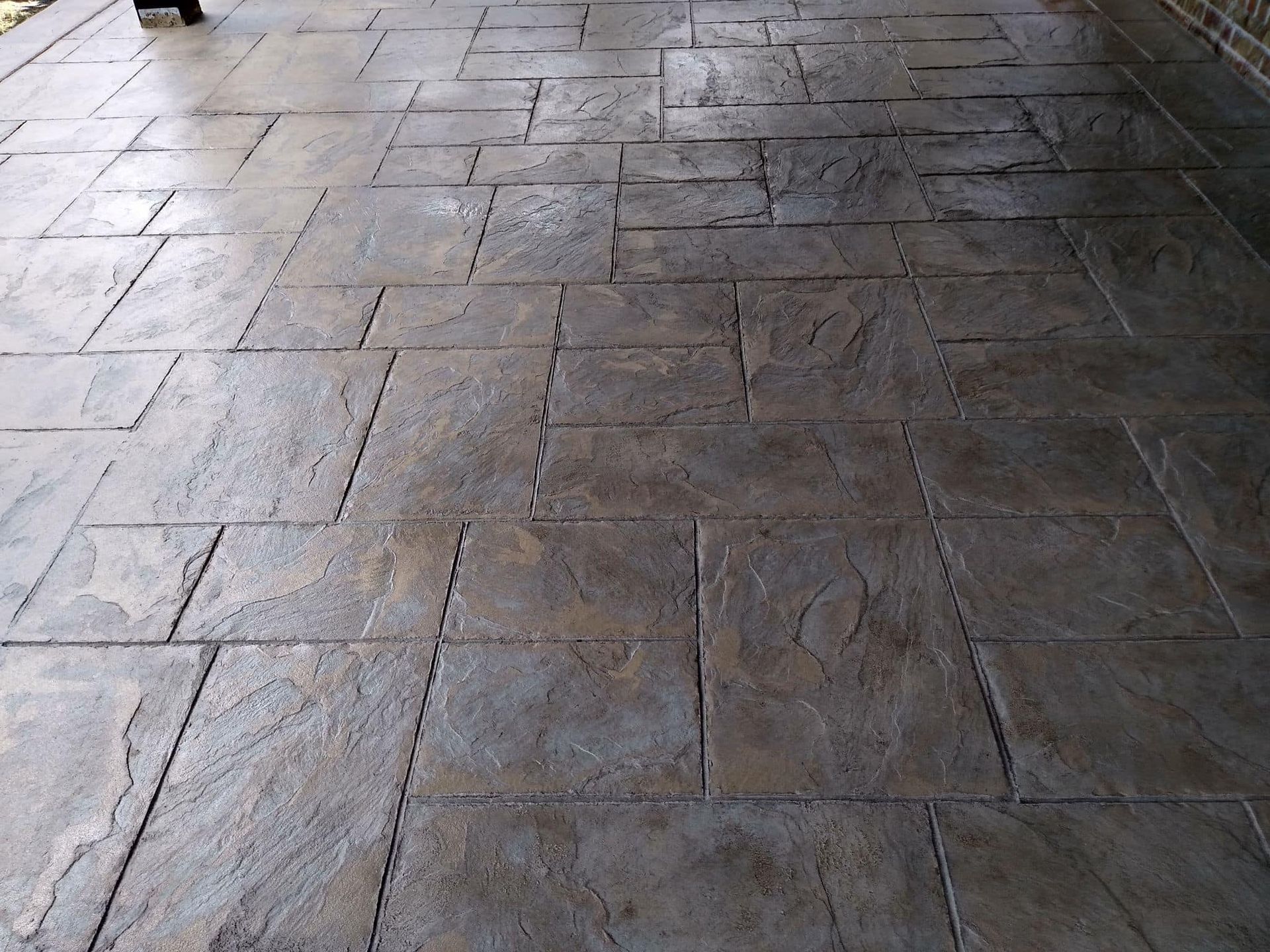Textured, dark gray stamped concrete patio with rectangular and square patterns.