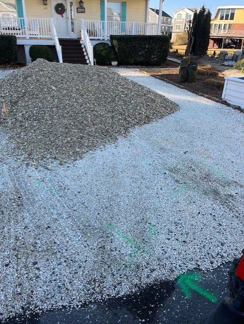 A pile of gravel is sitting in front of a house.