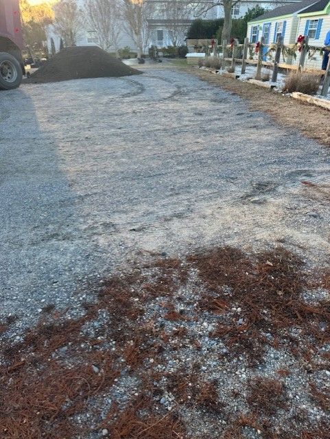 A truck is driving down a gravel road next to a house.