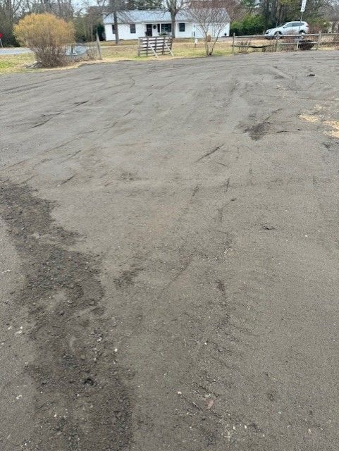 A large empty parking lot with a house in the background.
