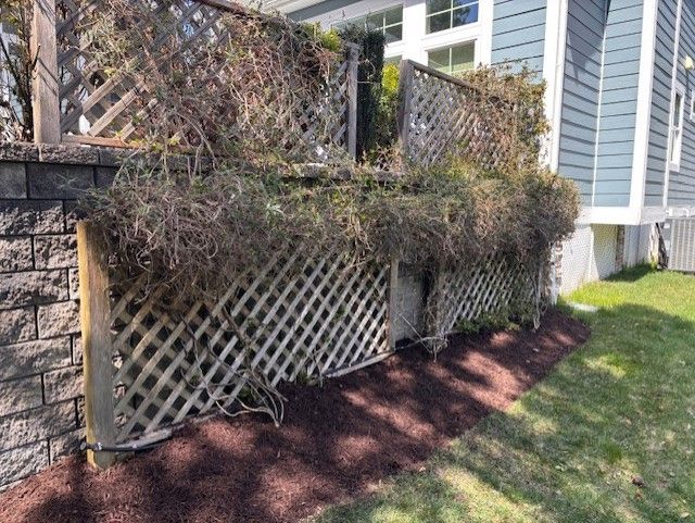 A fence with a trellis and a brick wall in front of a house.