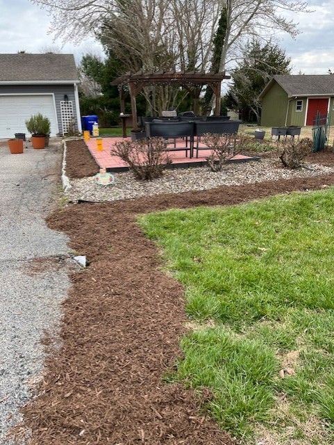 A lawn with a pergola in the background and a house in the background.