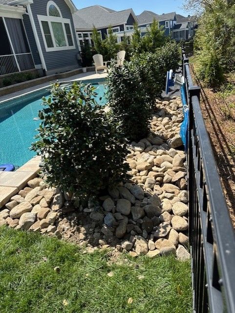 A fence surrounds a swimming pool with a house in the background.