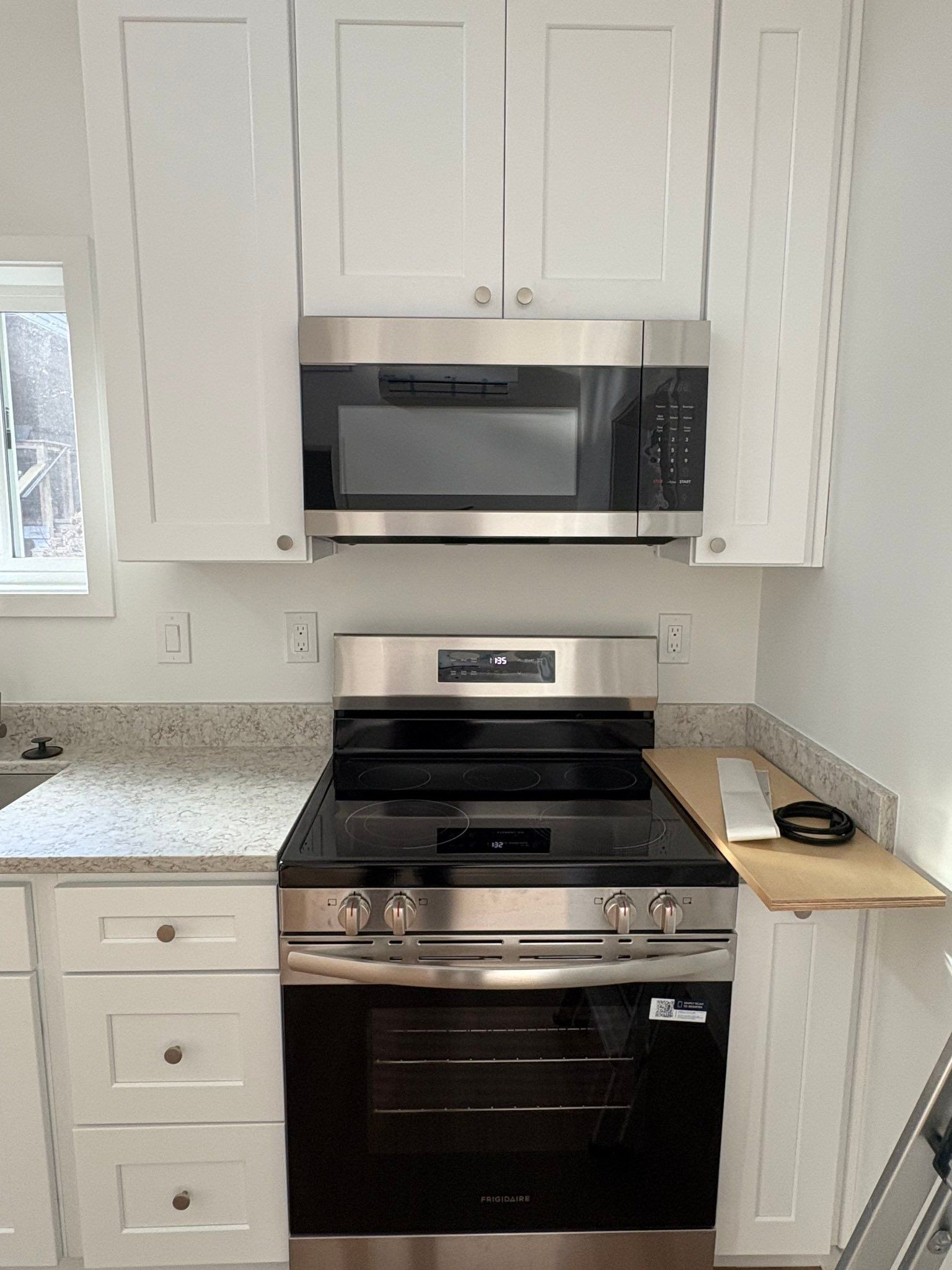 A modern dark blue shed with white trim, a small window, and sliding glass doors, situated on a stone patio with gravel.