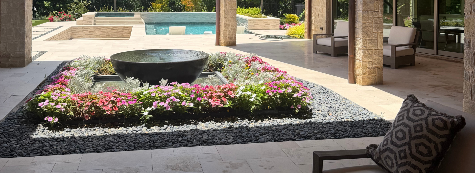 Bowl shaped water fountain surrounded by flowers in an outdoor living space