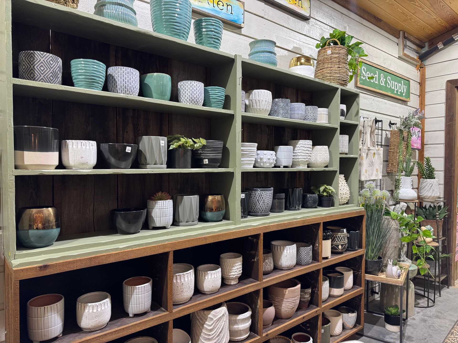Assorted ceramic pots and planters, Textured, ribbed, and patterned styles Colors: white, black, gray, tan, blush, teal, and green, Faux potted succulents in small planters, Woven basket planter with greenery (top shelf),
