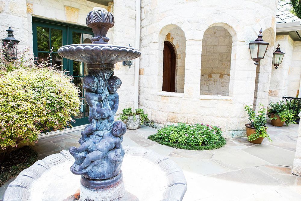 A fountain in the middle of the courtyard in front of a building