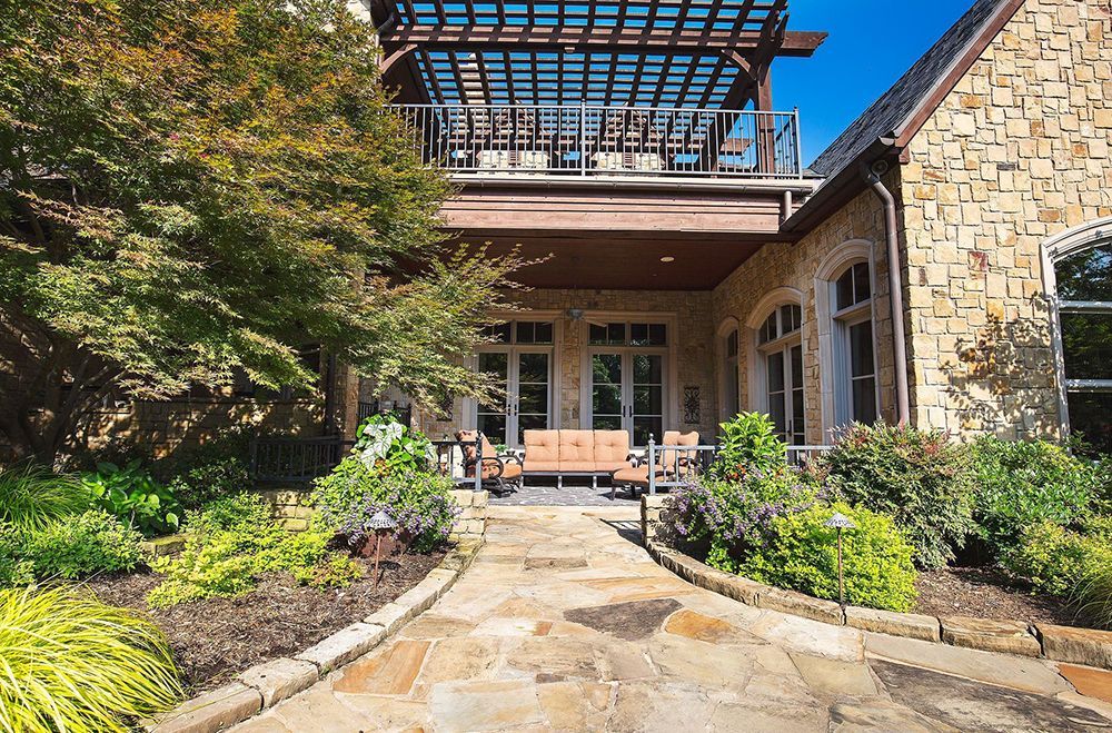 A stone walkway leading to a large house with a balcony
