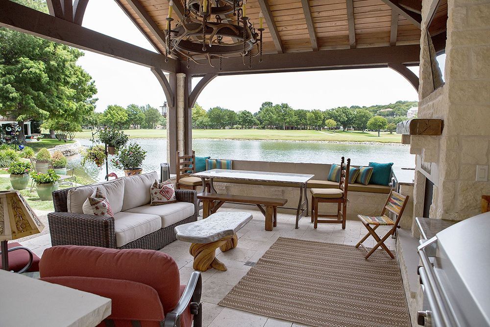 A living room with a couch, table, chairs and a fireplace overlooking a lake