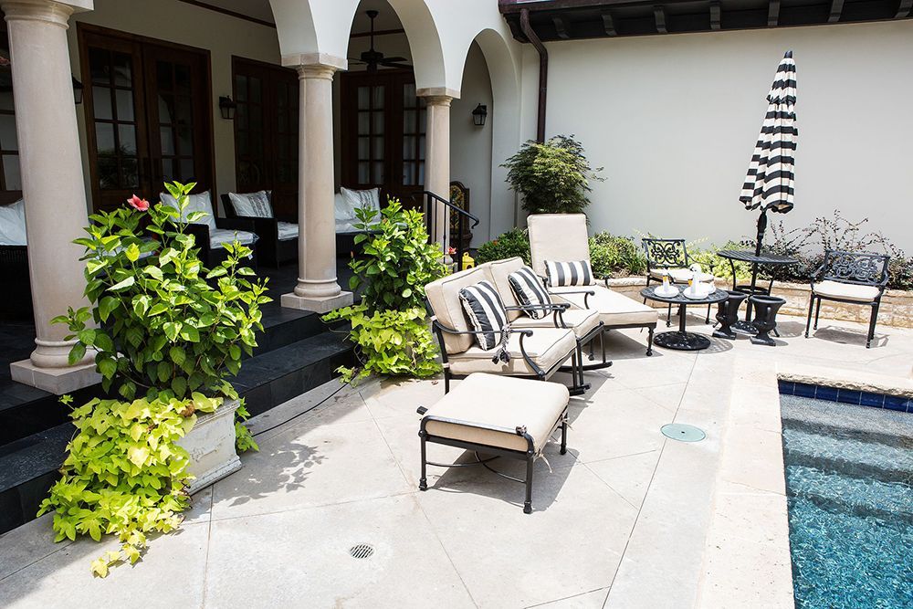 A patio with a couch and chairs next to a pool