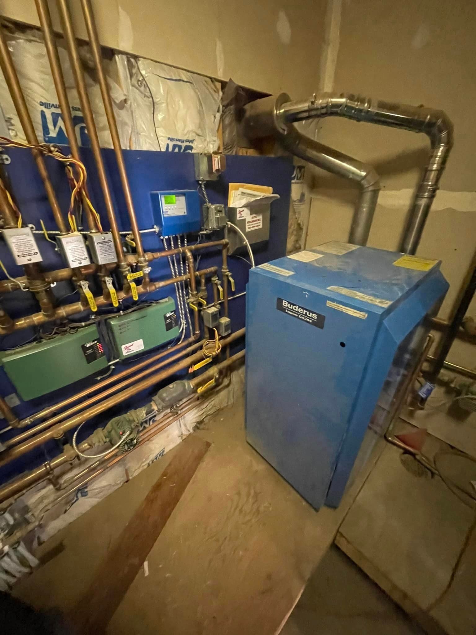Blue boiler and related plumbing against a wall with copper pipes and a ventilation flue.