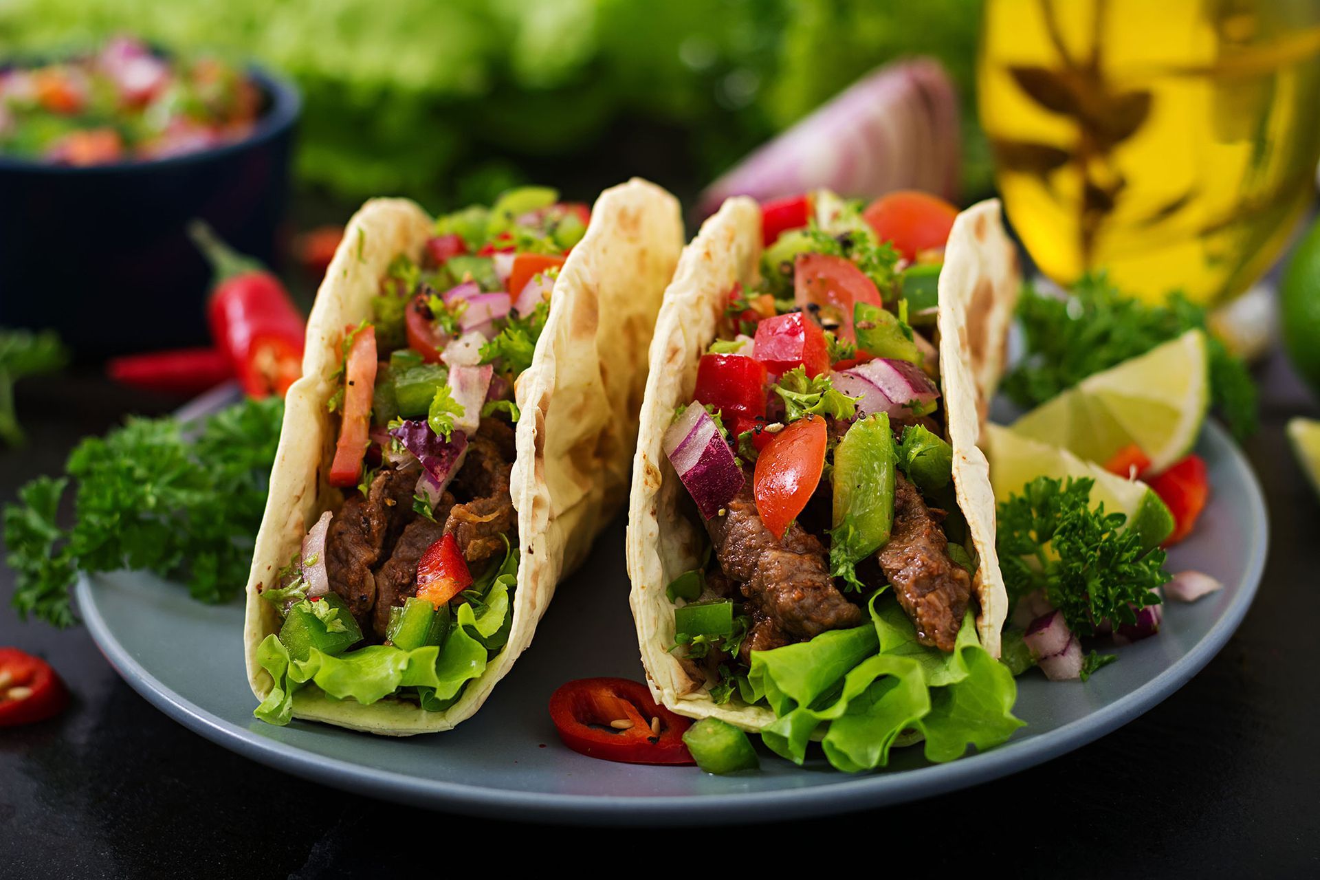 Three tacos with meat and vegetables on a plate.