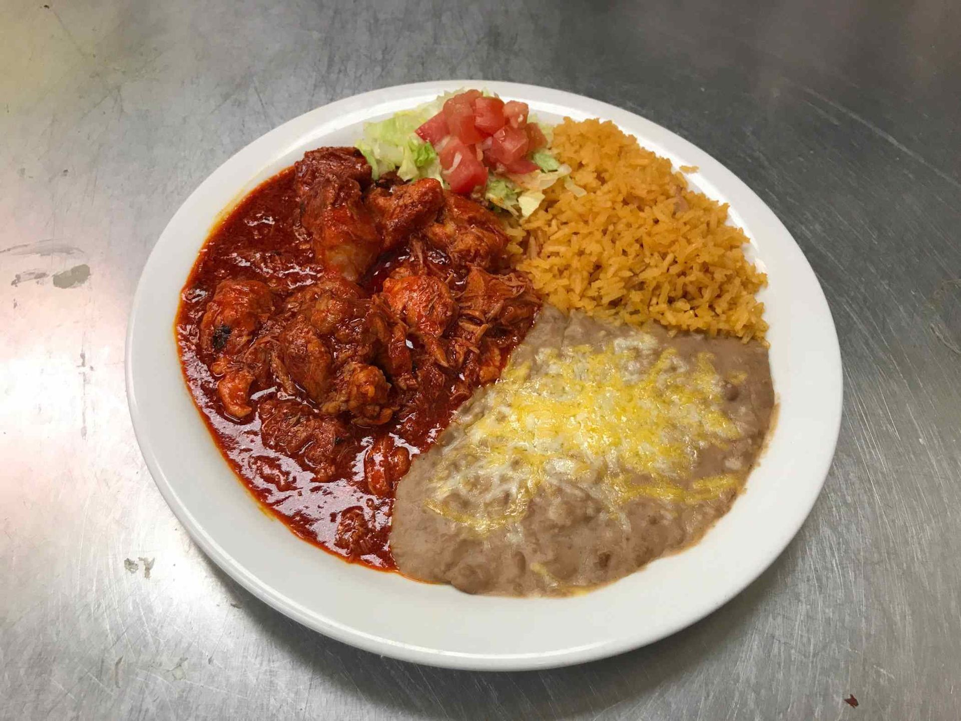A plate of mexican food with rice beans and cheese on a table.