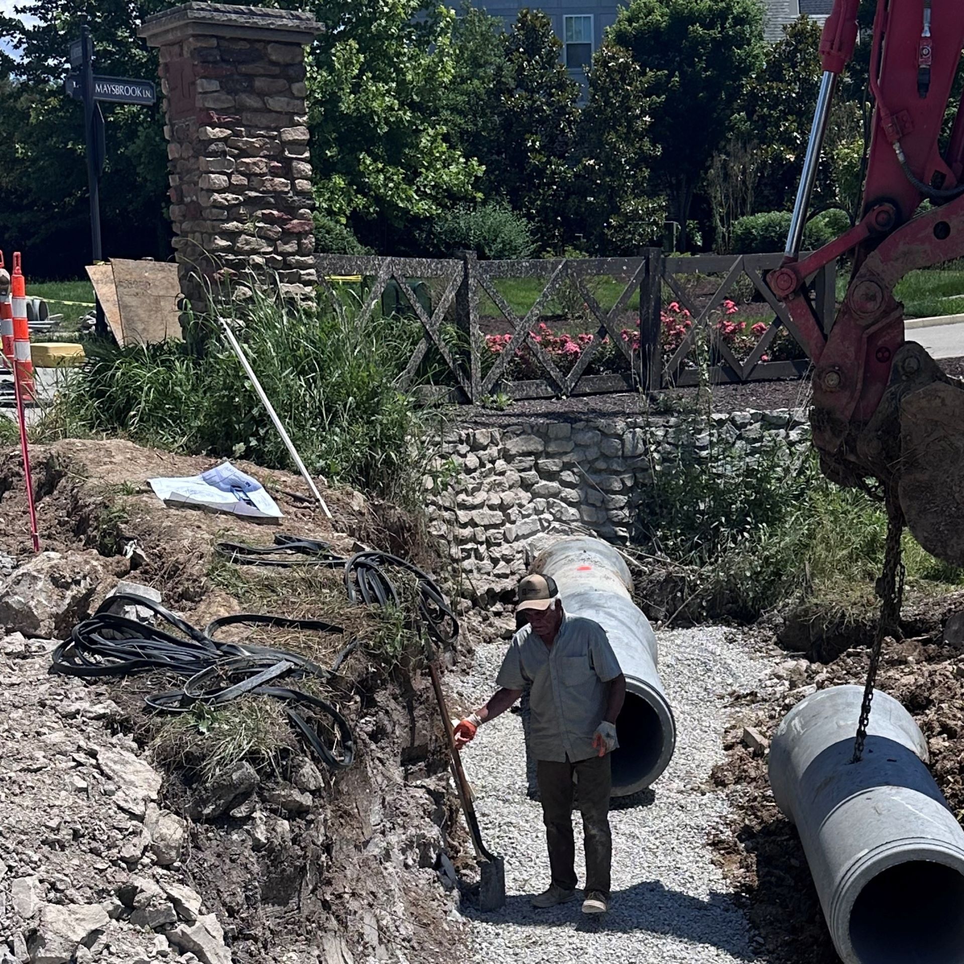 A man with a shovel is standing next to a large pipe