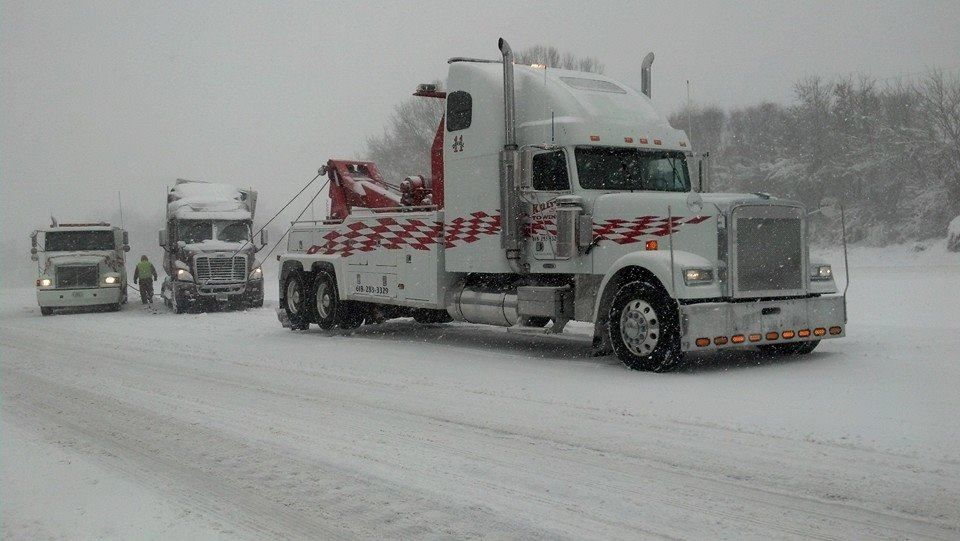 a tow truck is driving down a snowy highway