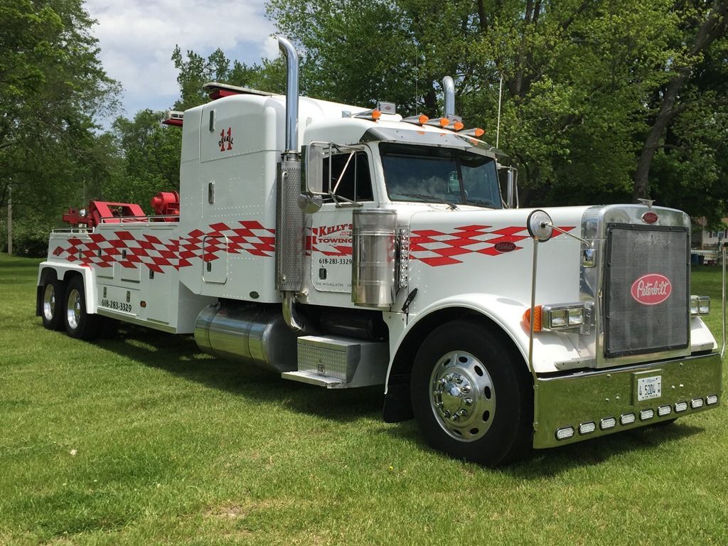 a white tow truck is parked in a grassy field
