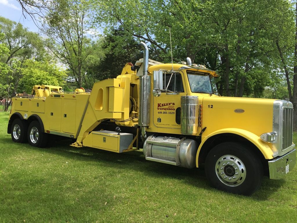 a yellow tow truck is parked in a grassy field