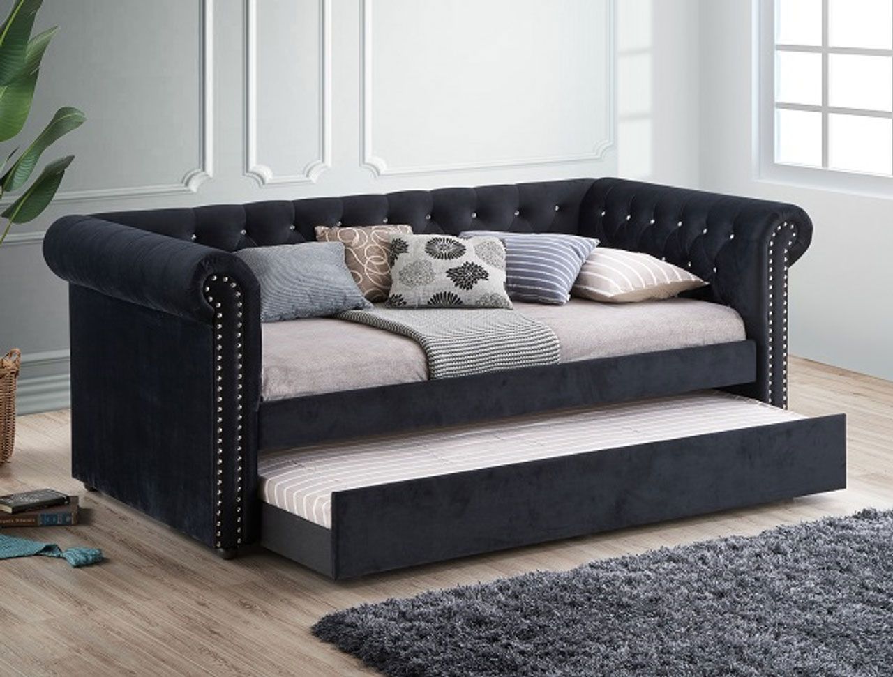 A black day bed with a pull out bed underneath it in a living room.