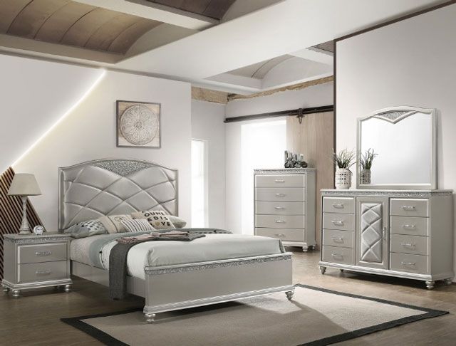 A bedroom with a bed , dresser , nightstand and mirror.