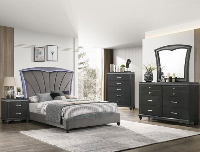 A bedroom with a bed , dresser , mirror and nightstand.