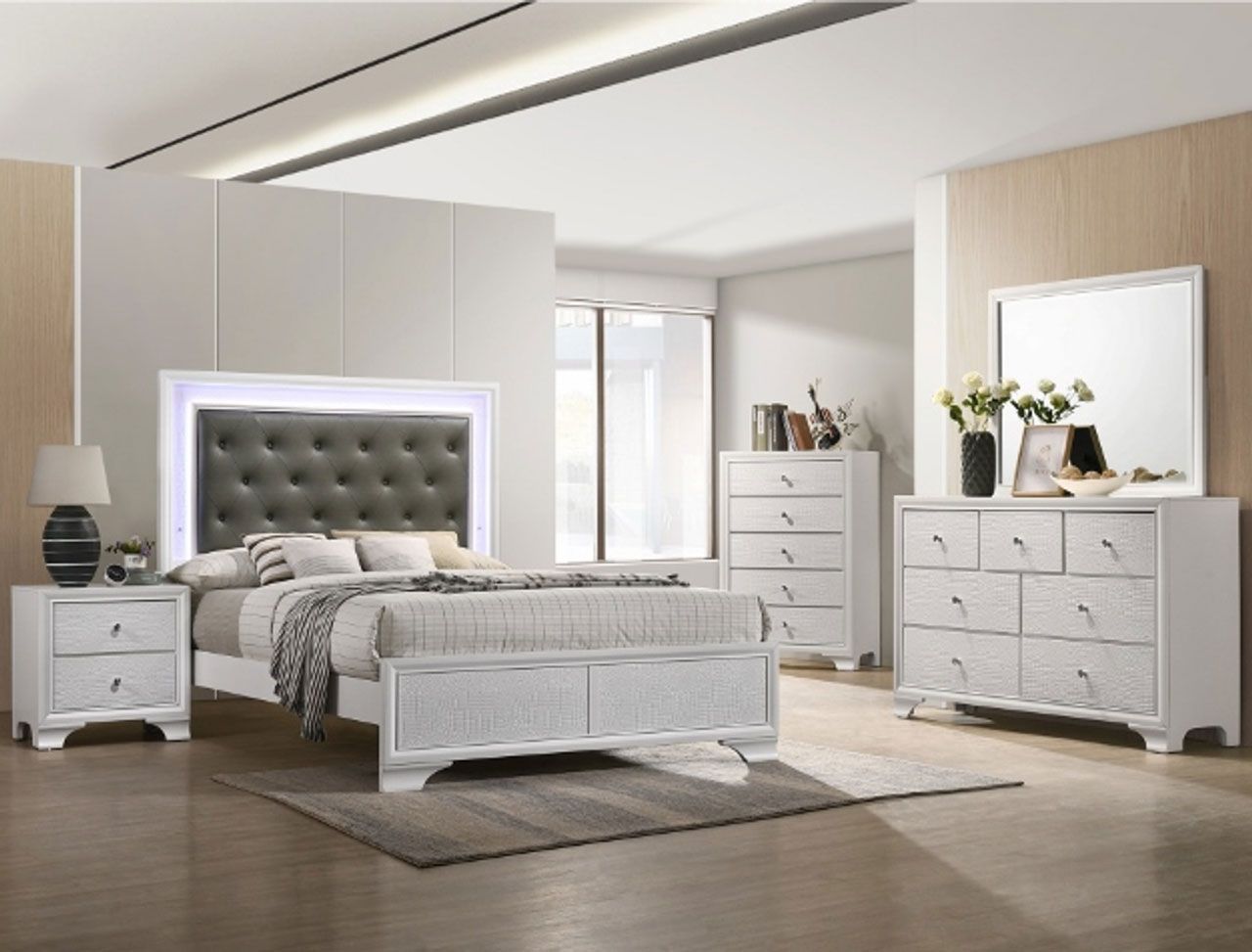 A bedroom with a bed , dresser , nightstand and mirror.