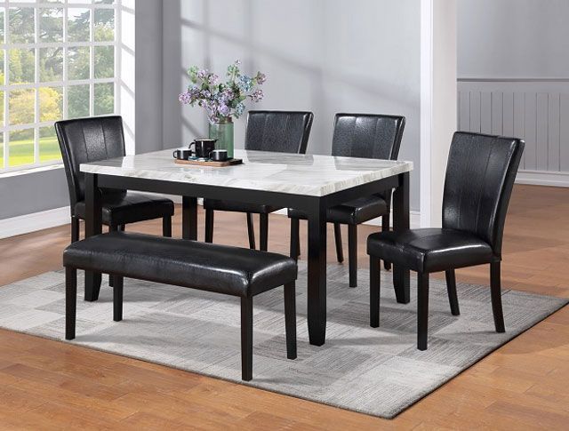 A dining room table with black chairs and a bench.