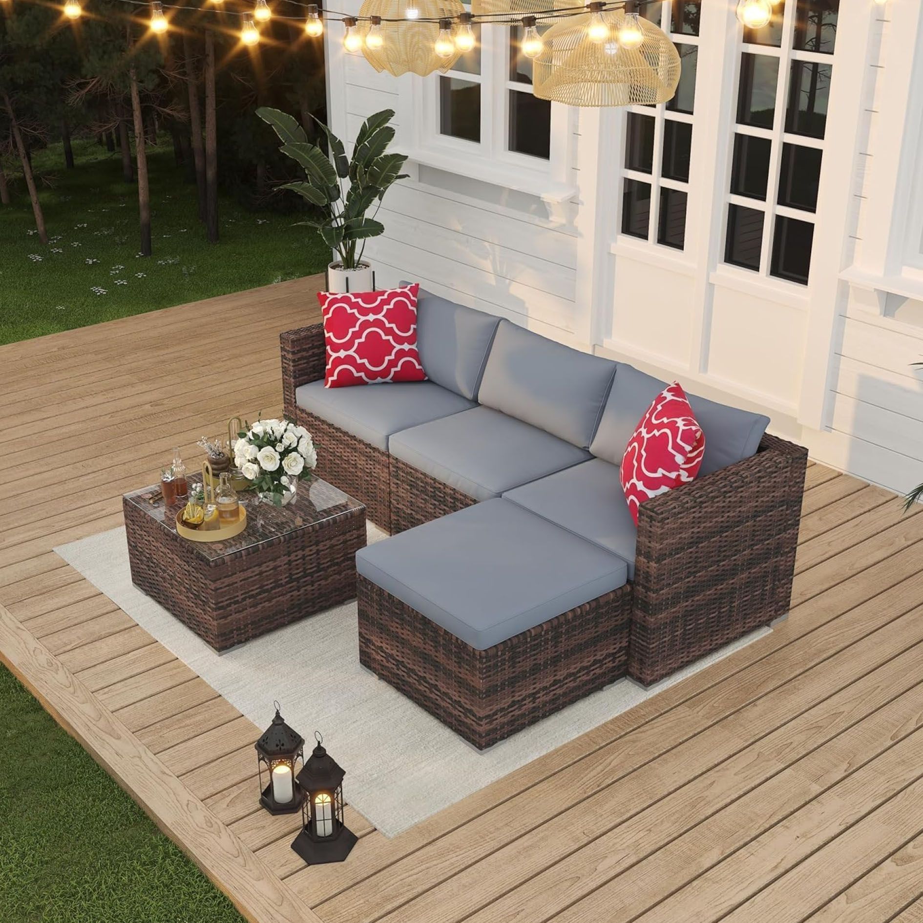 Outdoor patio set with a brown wicker sectional sofa, coffee table, and two patterned throw pillows on a wooden deck.