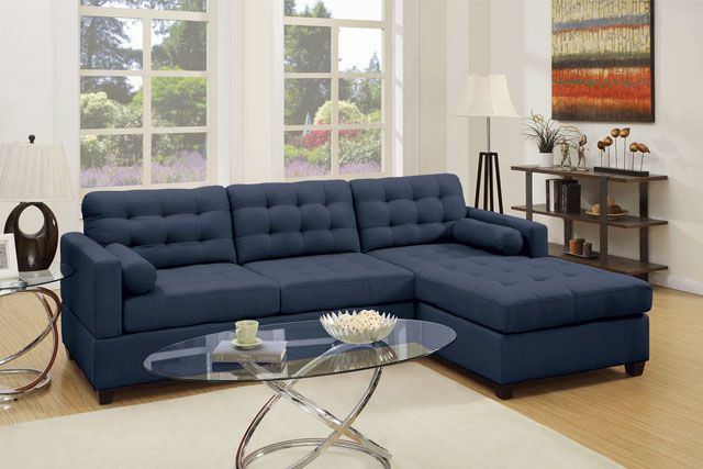 A living room with a blue sectional couch and a glass coffee table