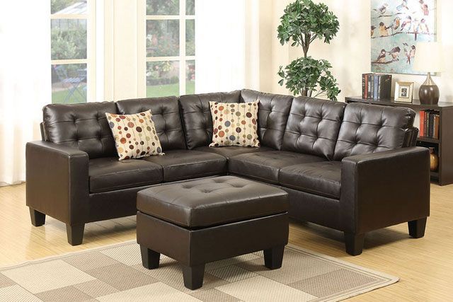 A living room with a brown leather sectional couch and ottoman.
