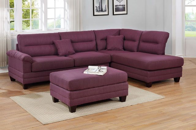 A living room with a purple sectional couch and ottoman
