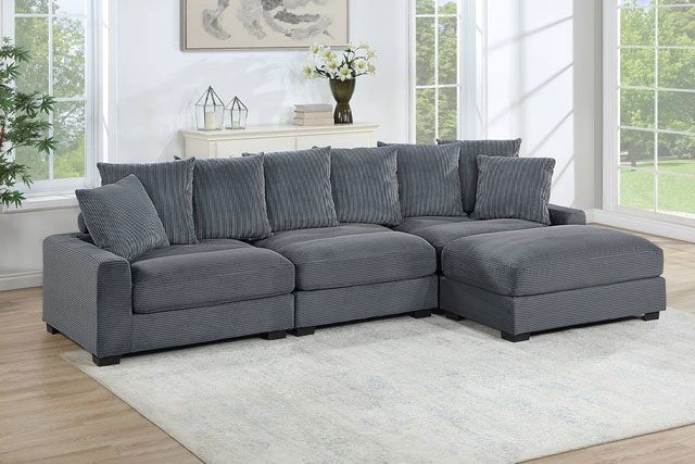 A large grey sectional couch is sitting on top of a white rug in a living room.