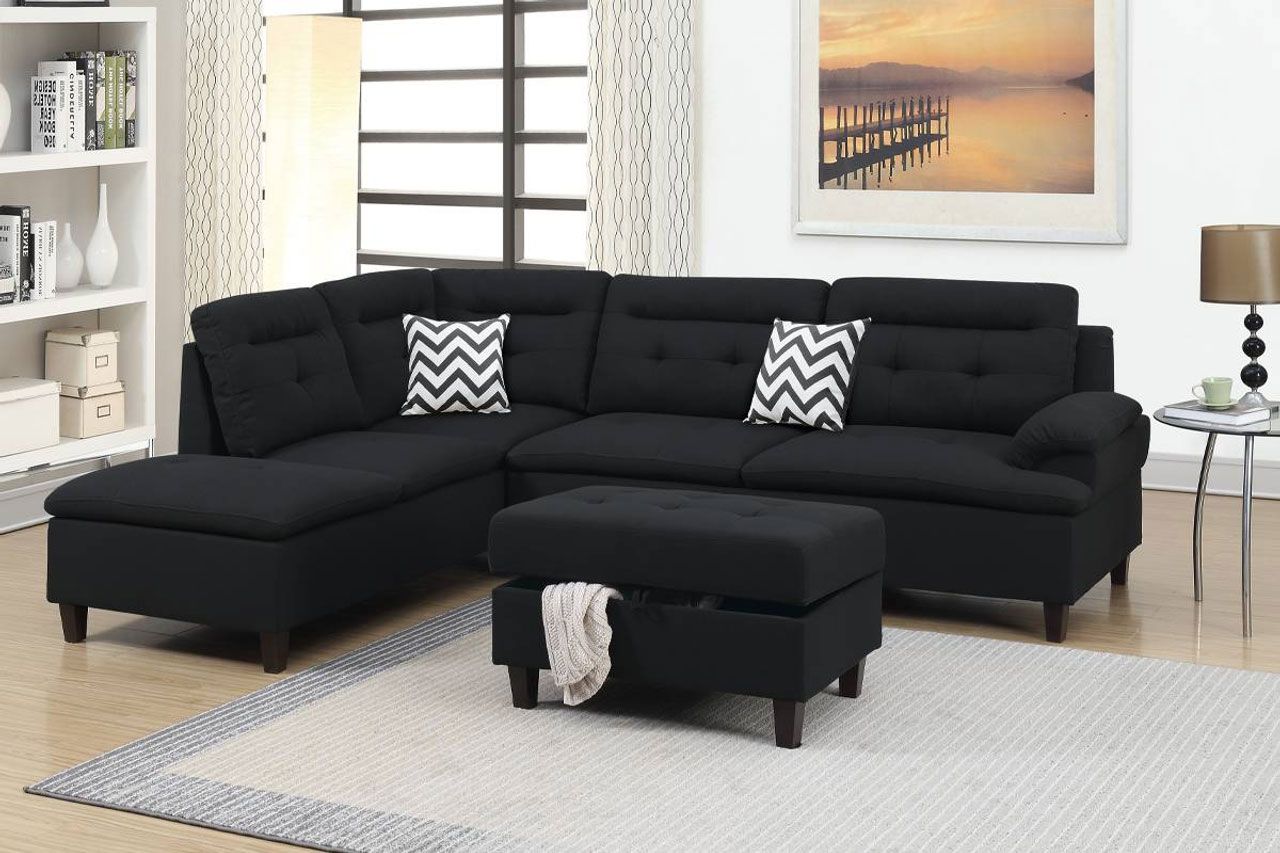 A living room with a black sectional couch and ottoman