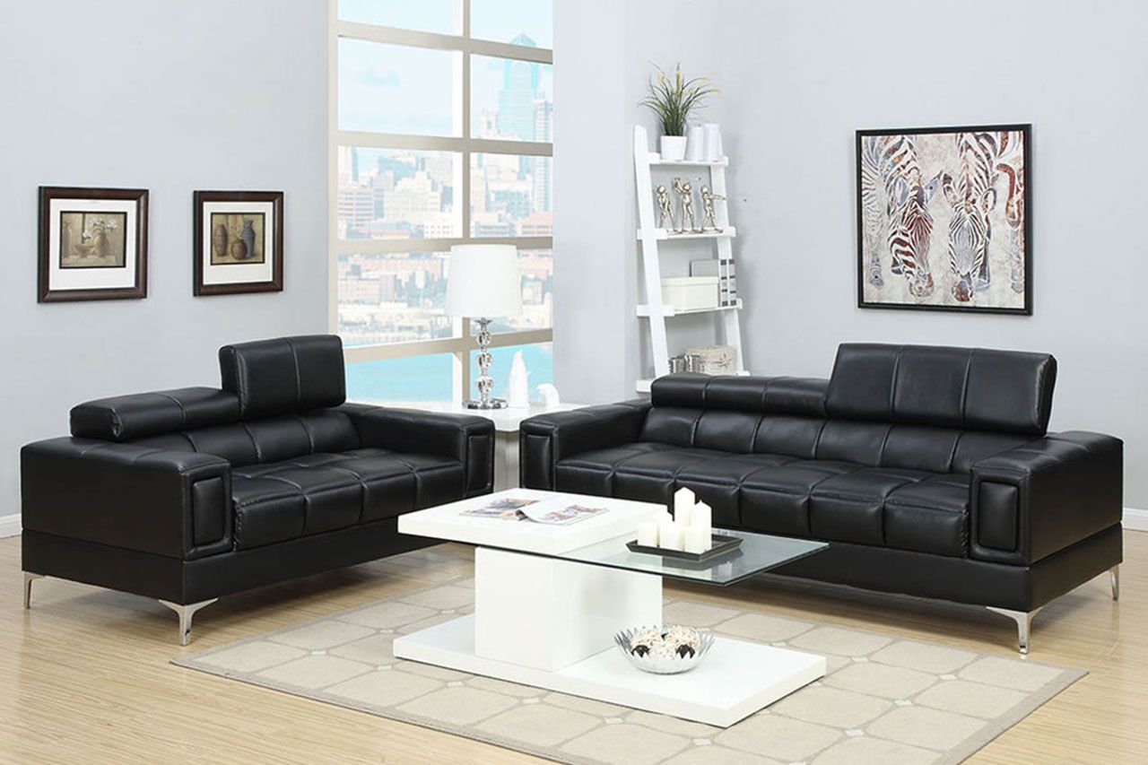 A living room with two black couches and a white coffee table