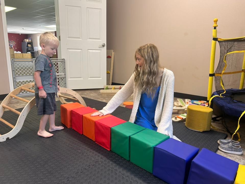 Child and teacher playing with colorful blocks in a pre-school room.