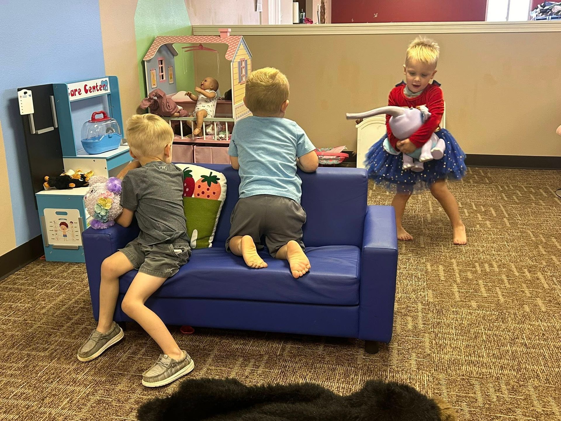 Three young children playing in a playroom.
