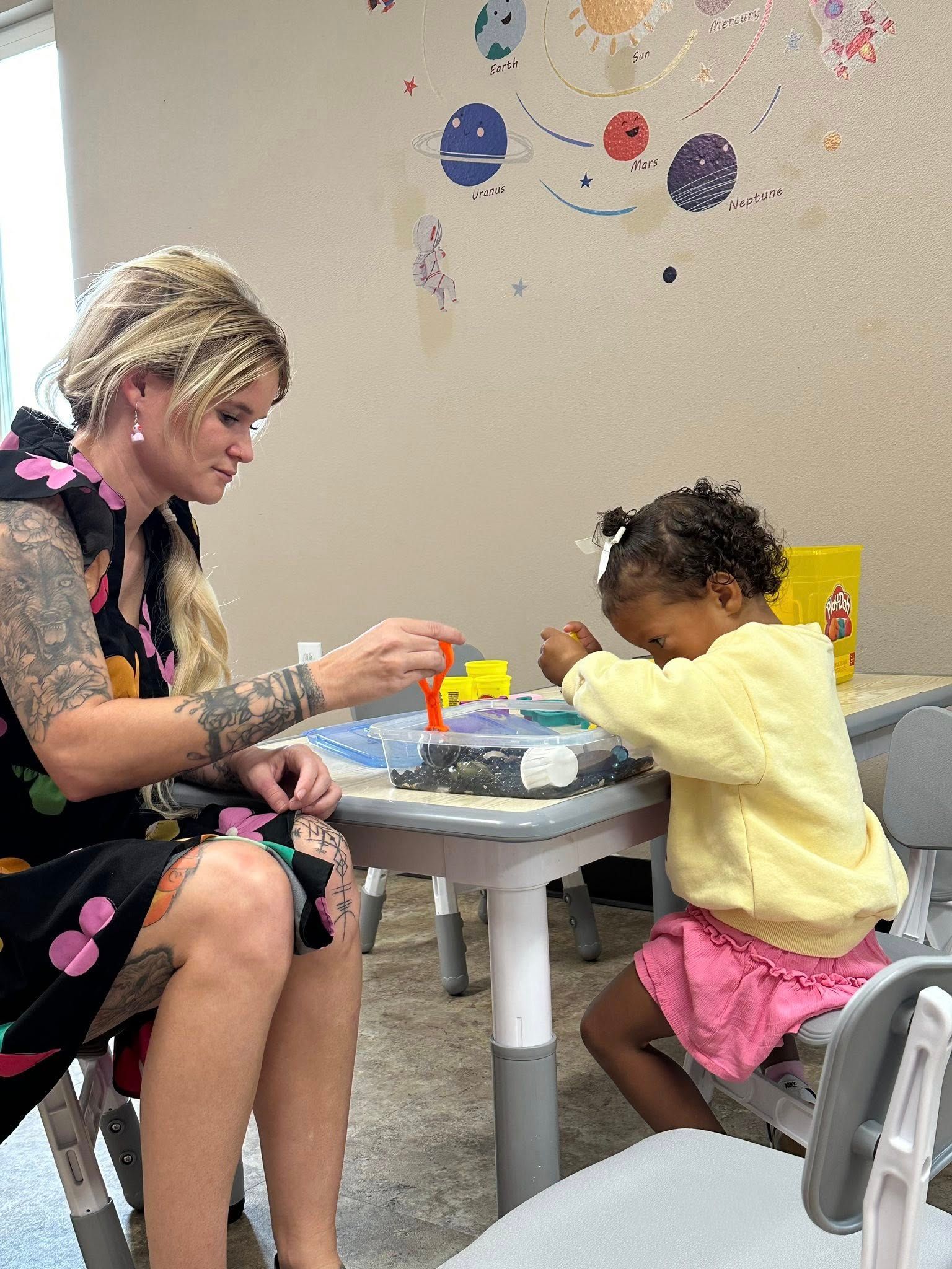 Woman with plays with a child at a table in a room. 