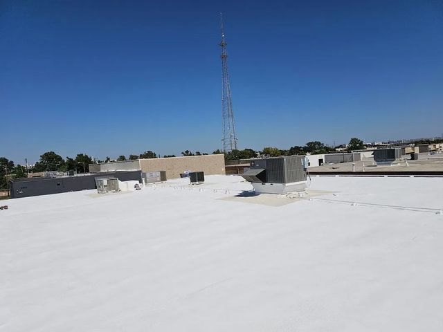 Flat white rooftop with vents and a tall communication tower under a clear blue sky.