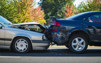 Two cars are involved in a car accident on the side of the road.