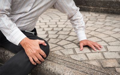 A man is sitting on the ground with his hands on his knees.