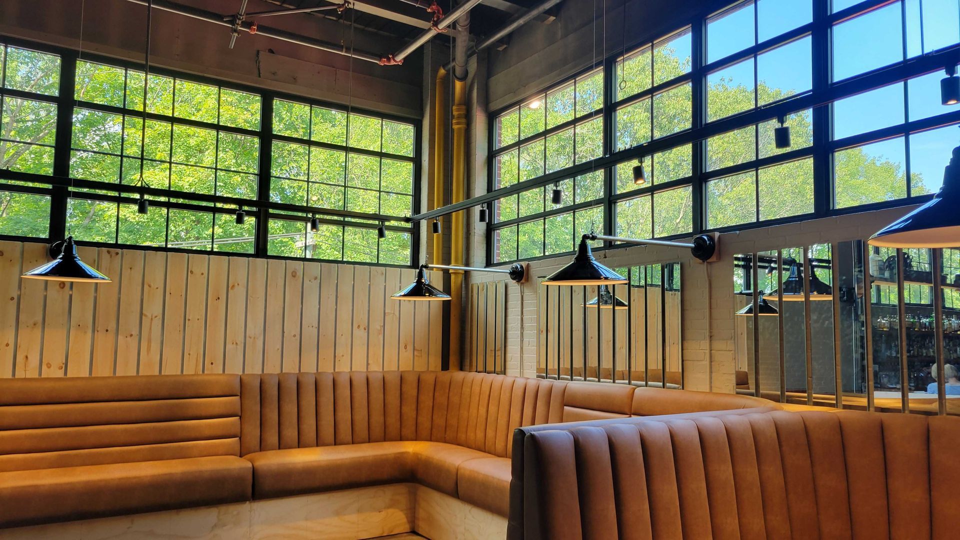 Restaurant interior with booth seating and large windows overlooking greenery.