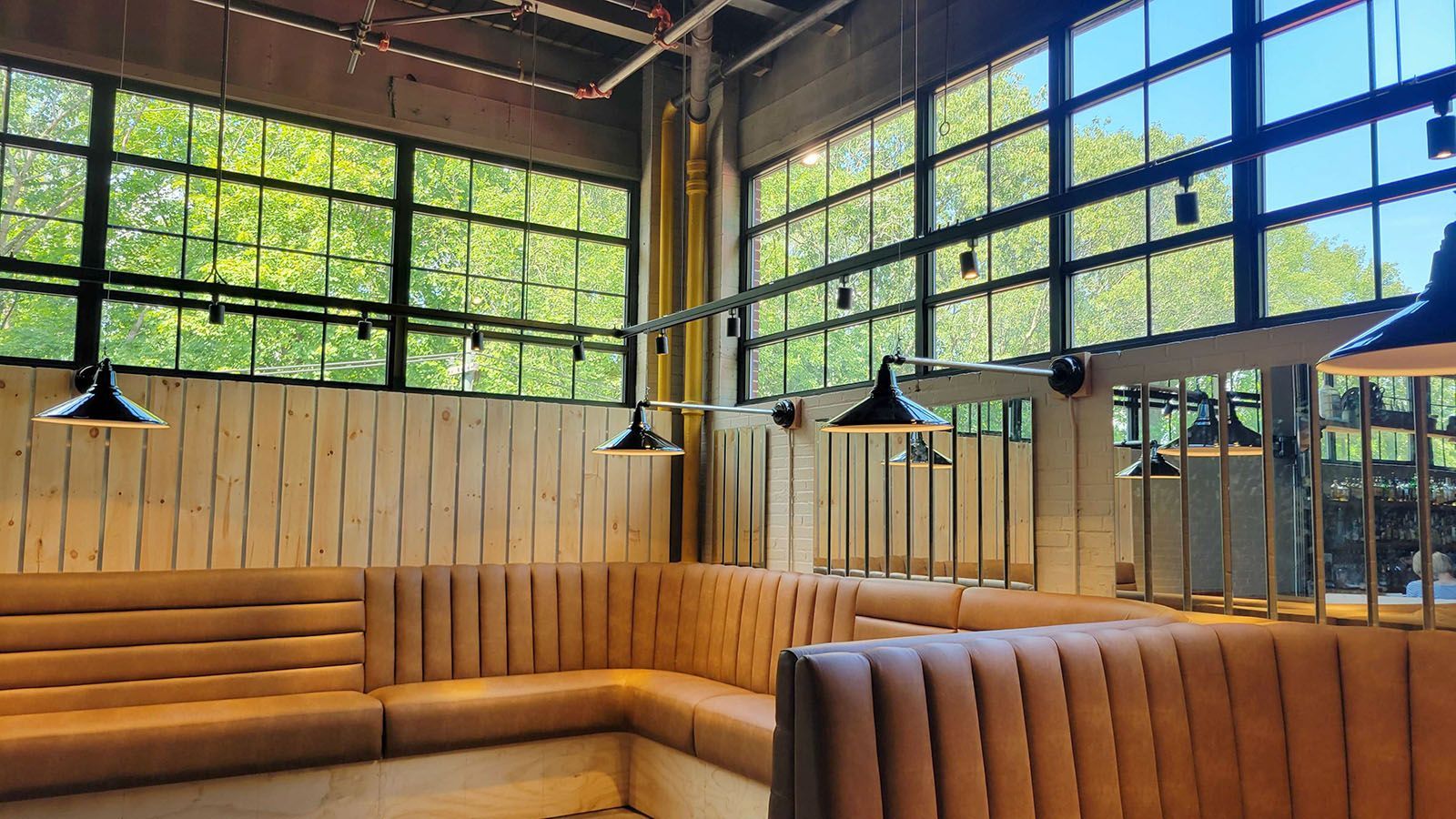 Restaurant interior with warm wood and tan tones with black light fixtures.