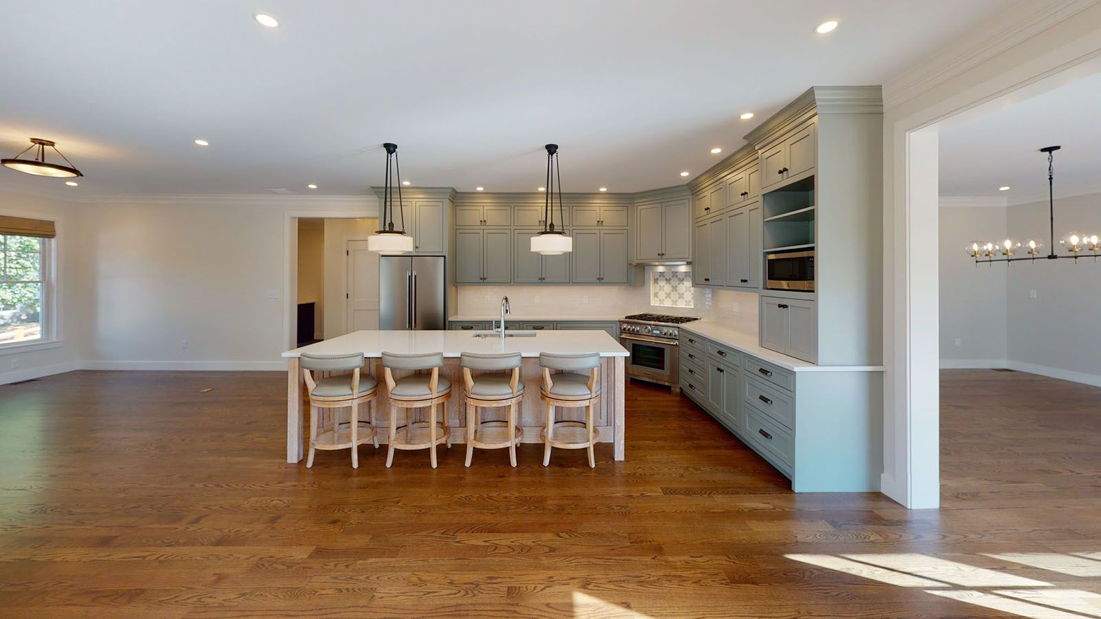 Well-lighted open kitchen with large island, light blue cabinets, and hardwood floors