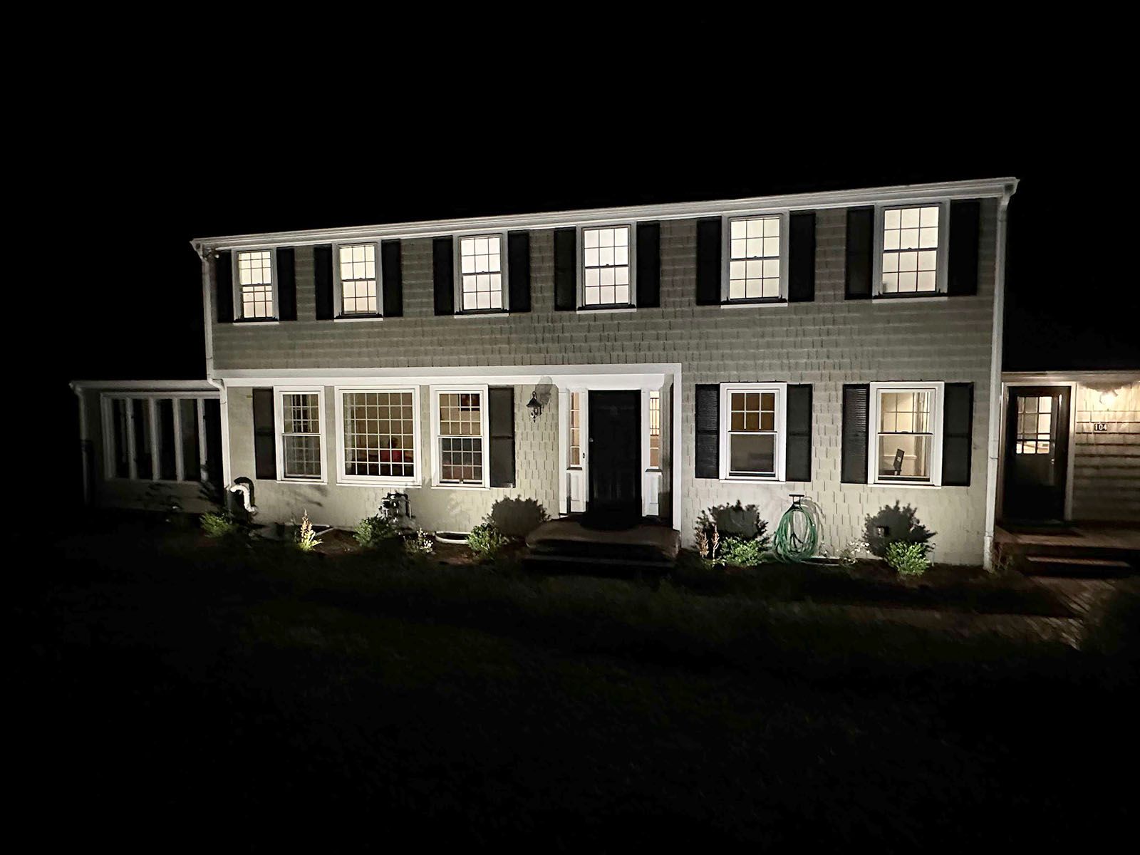 Two-story house at night; exterior illuminated by lights