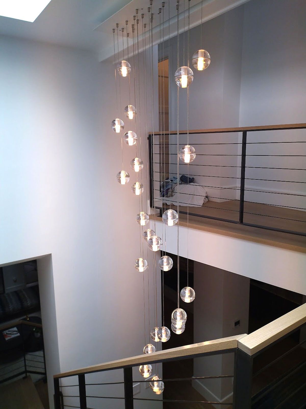 Modern staircase with a spiral light fixture of glass orbs